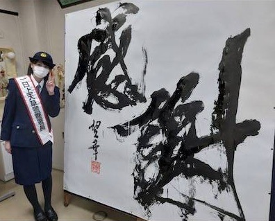 作成した書道パフォーマンスの作品とともに笑顔で写る村上さん